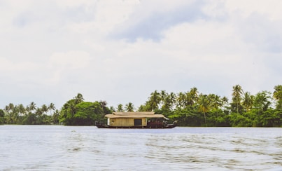 A houseboat traveling down a river with trees in the background
