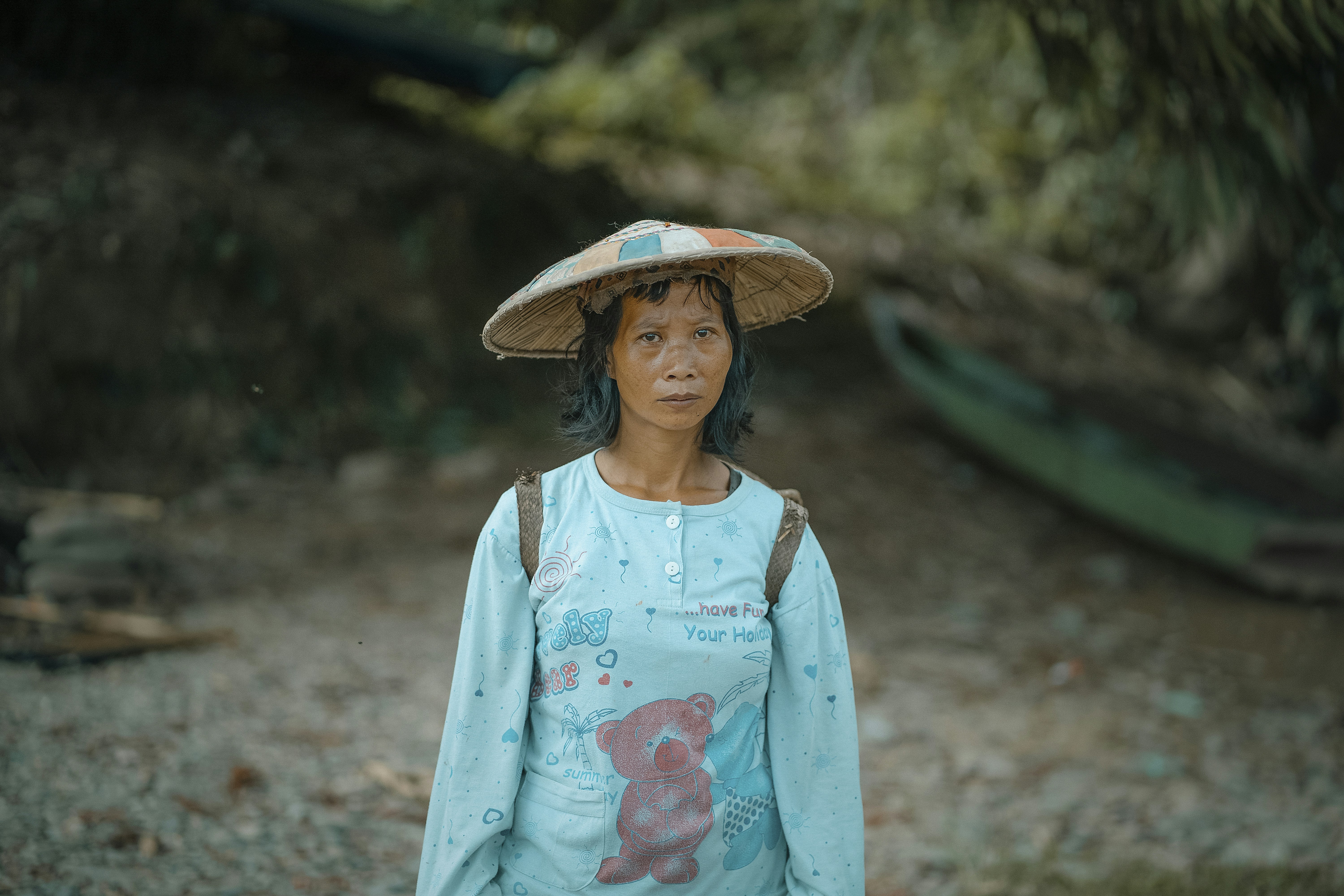 A woman wearing a hat standing on a dirt road
