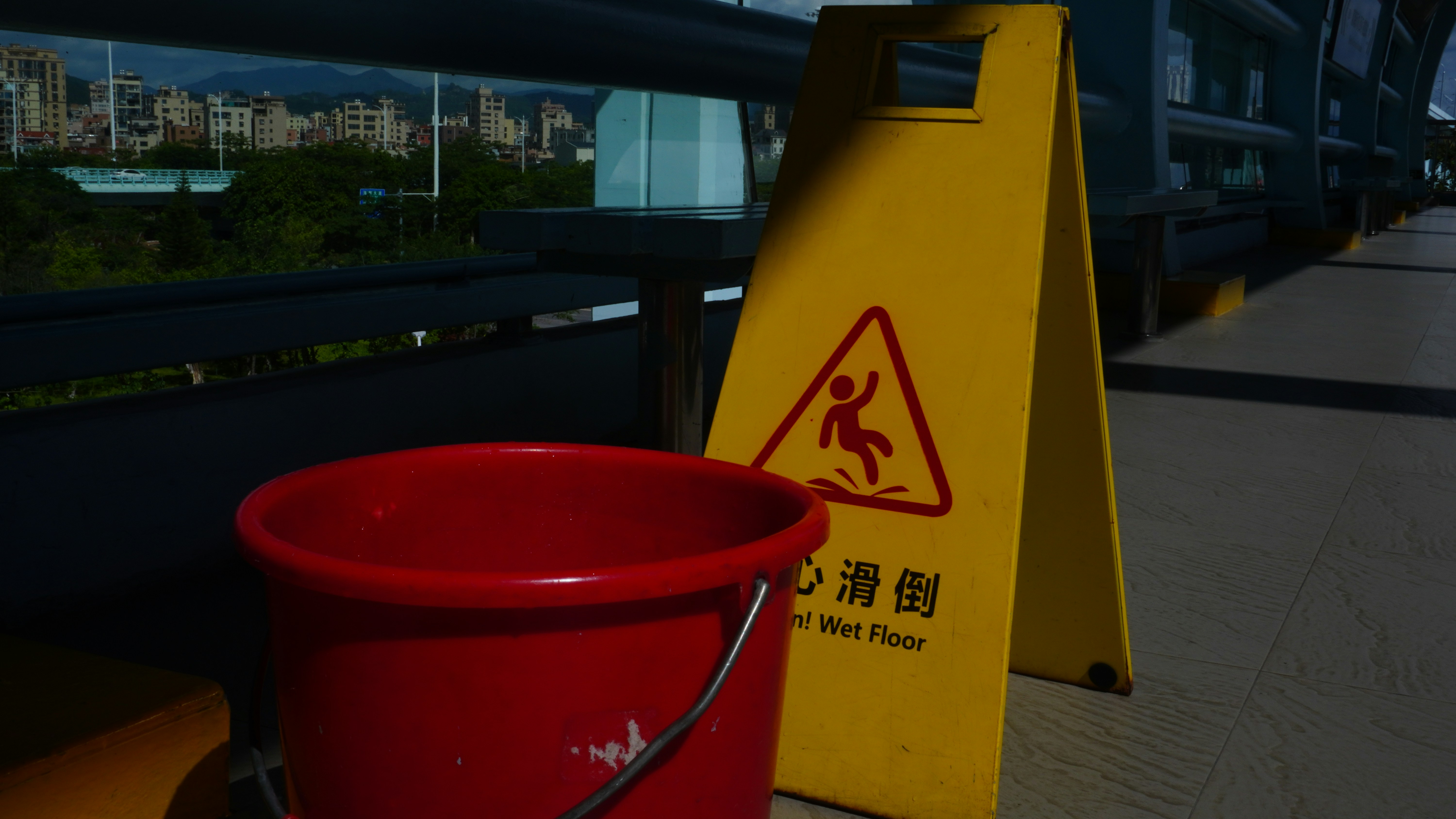 A red bucket sitting next to a yellow caution sign