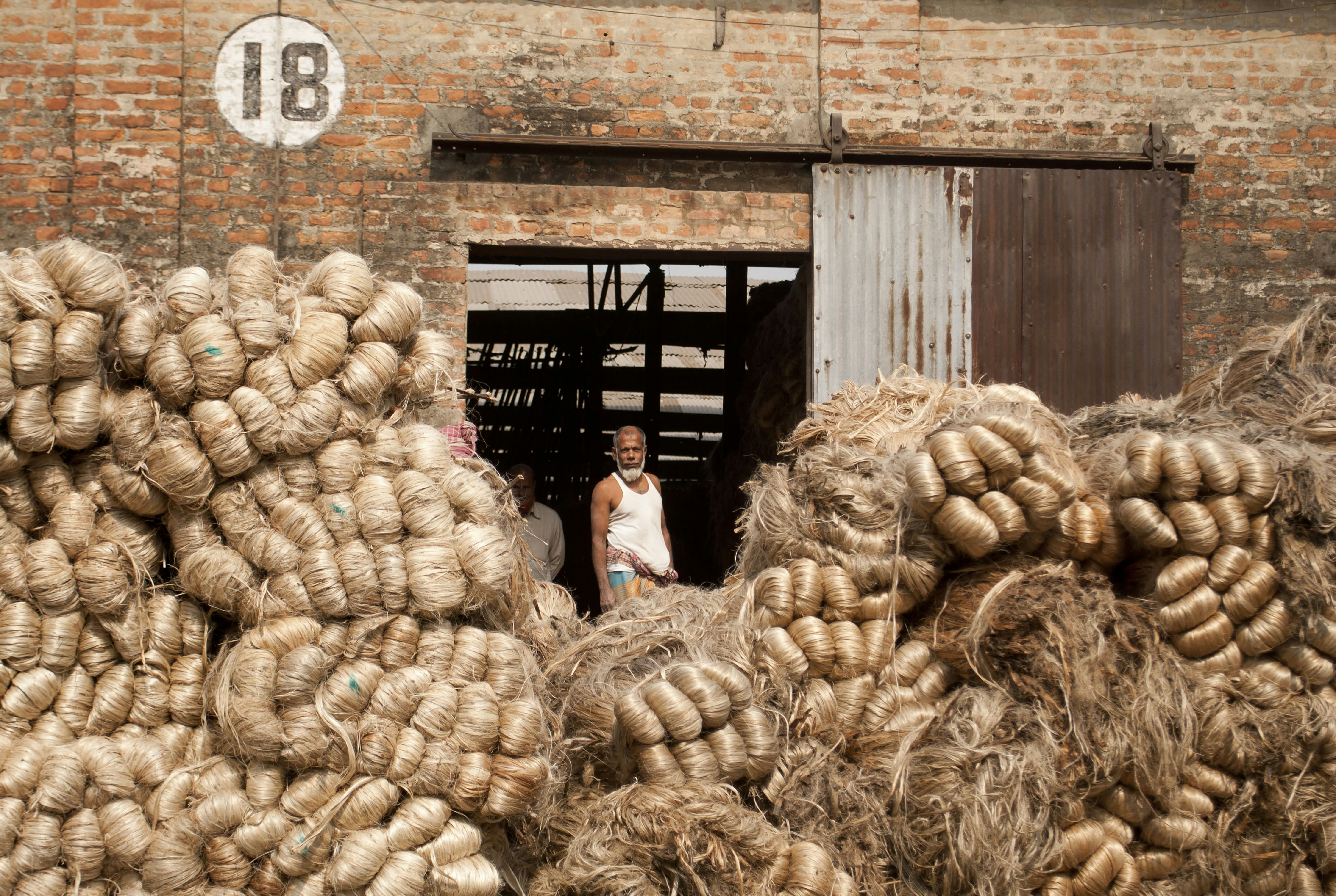 Farmers happily loading sacks of onions onto a truck at a procurement centre.