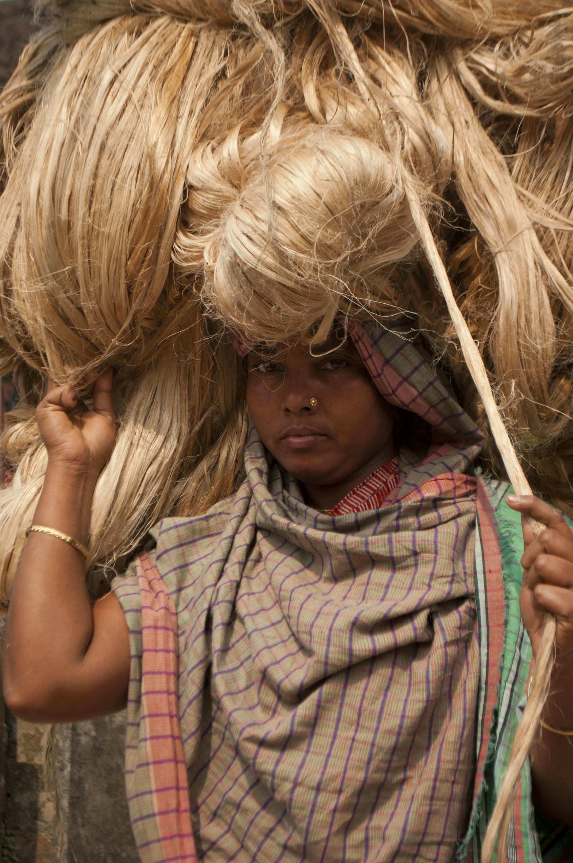 A woman carrying a bundle of hay on her head