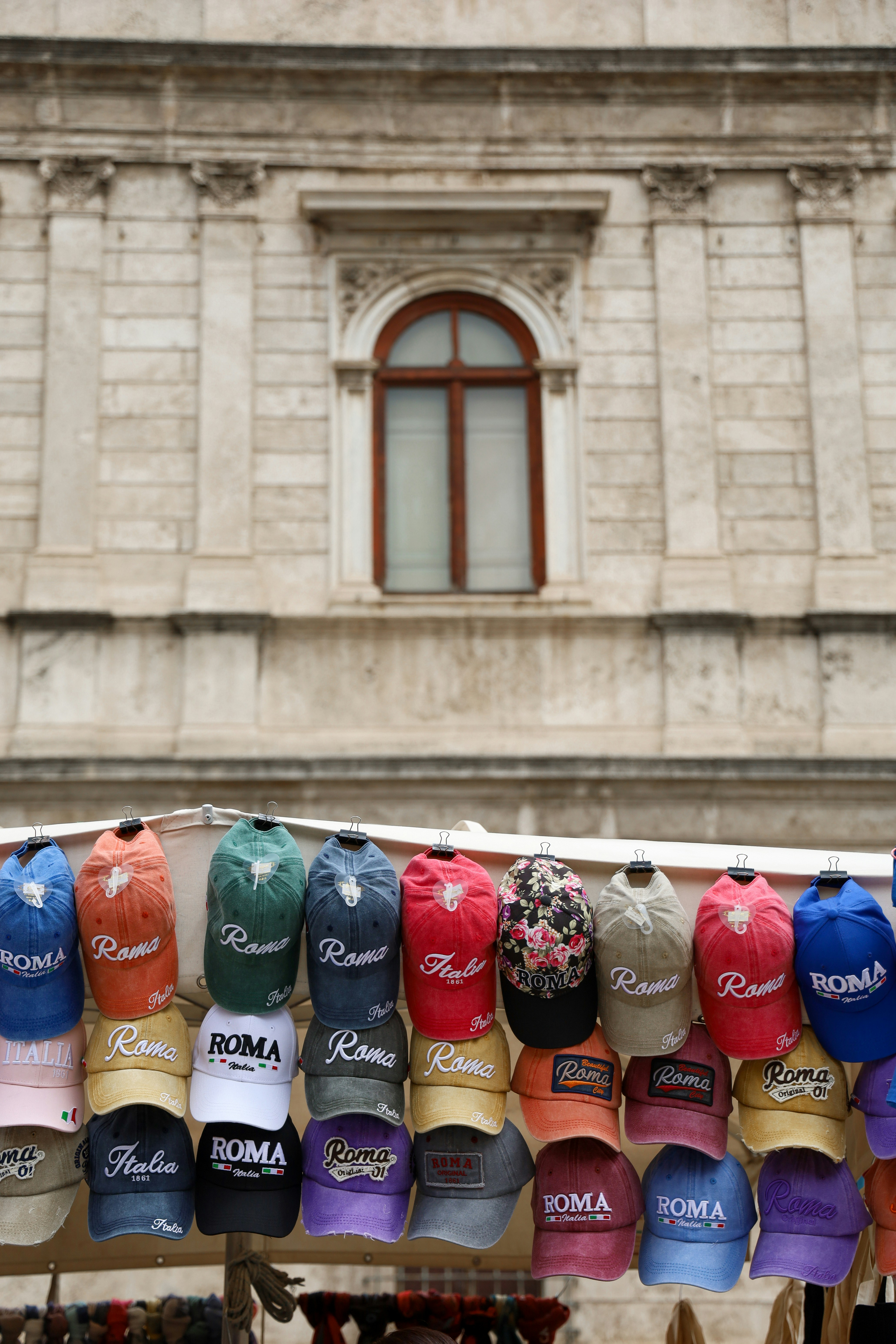 A row of hats hanging on a clothes line in front of a building