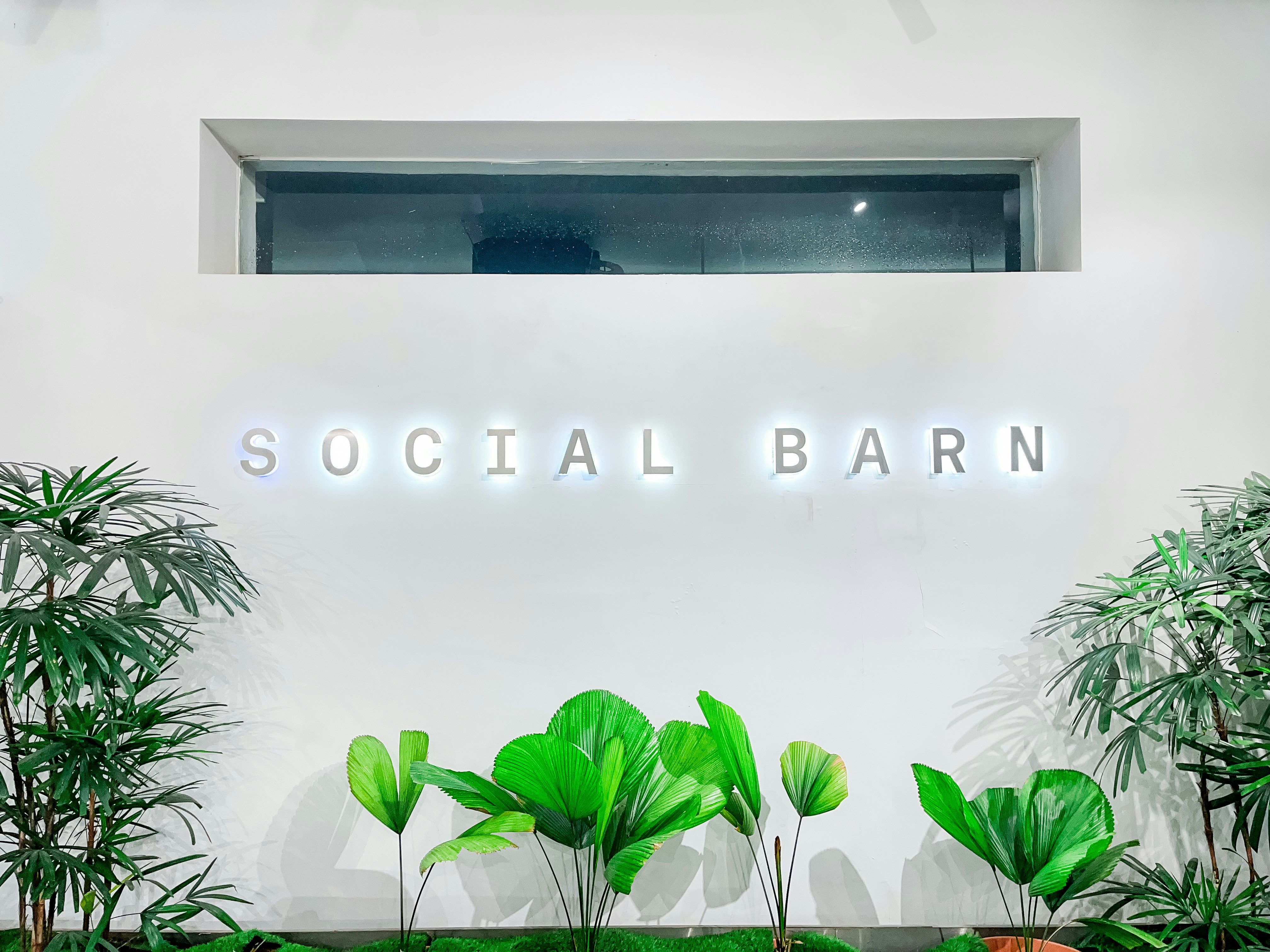 A white wall with a neon sign that says social barn