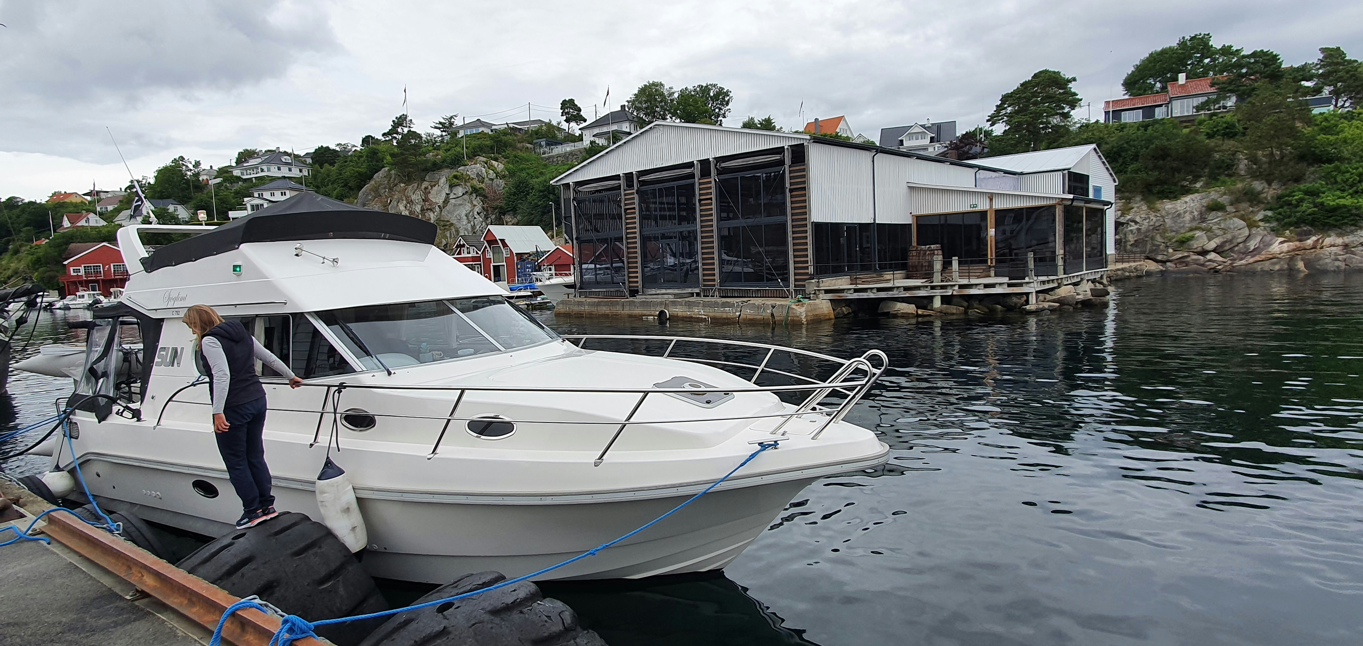A white boat tied to a dock with a man standing next to it