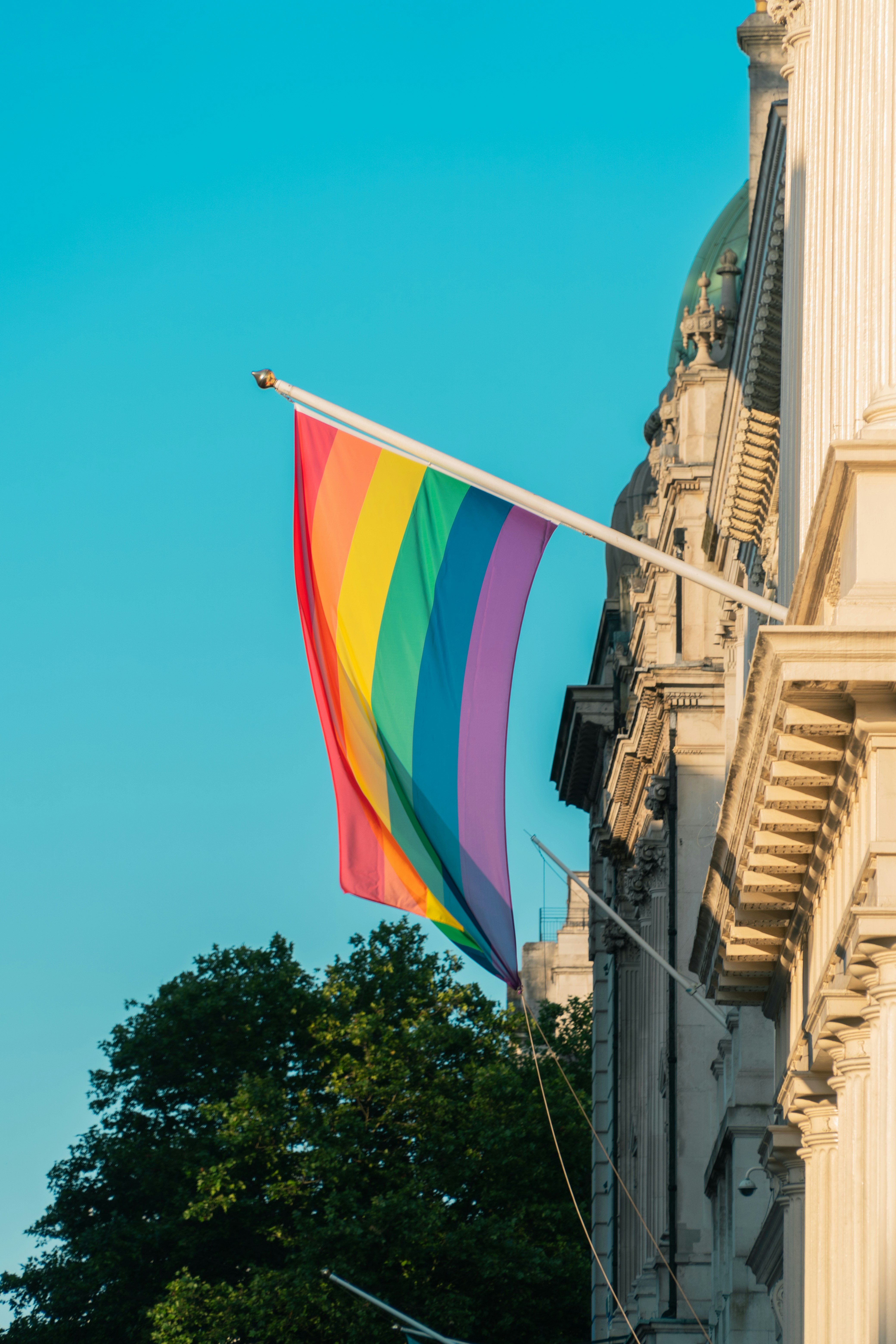A rainbow flag flying in front of a building
