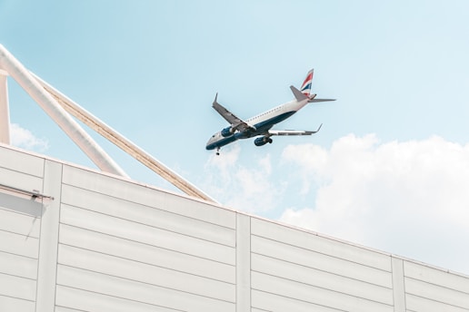 An airplane is flying over a white building