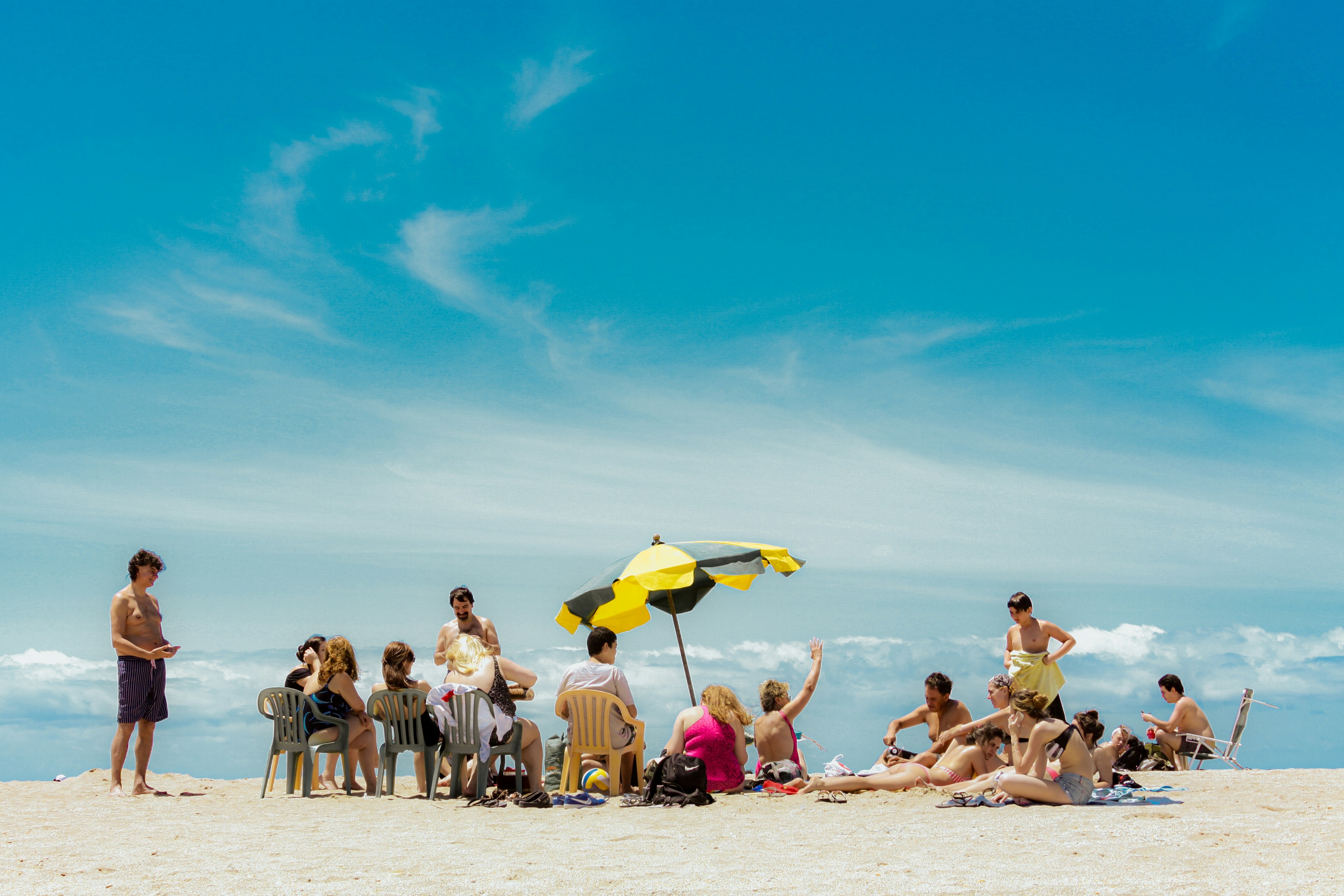 A group of people sitting on top of a sandy beach
