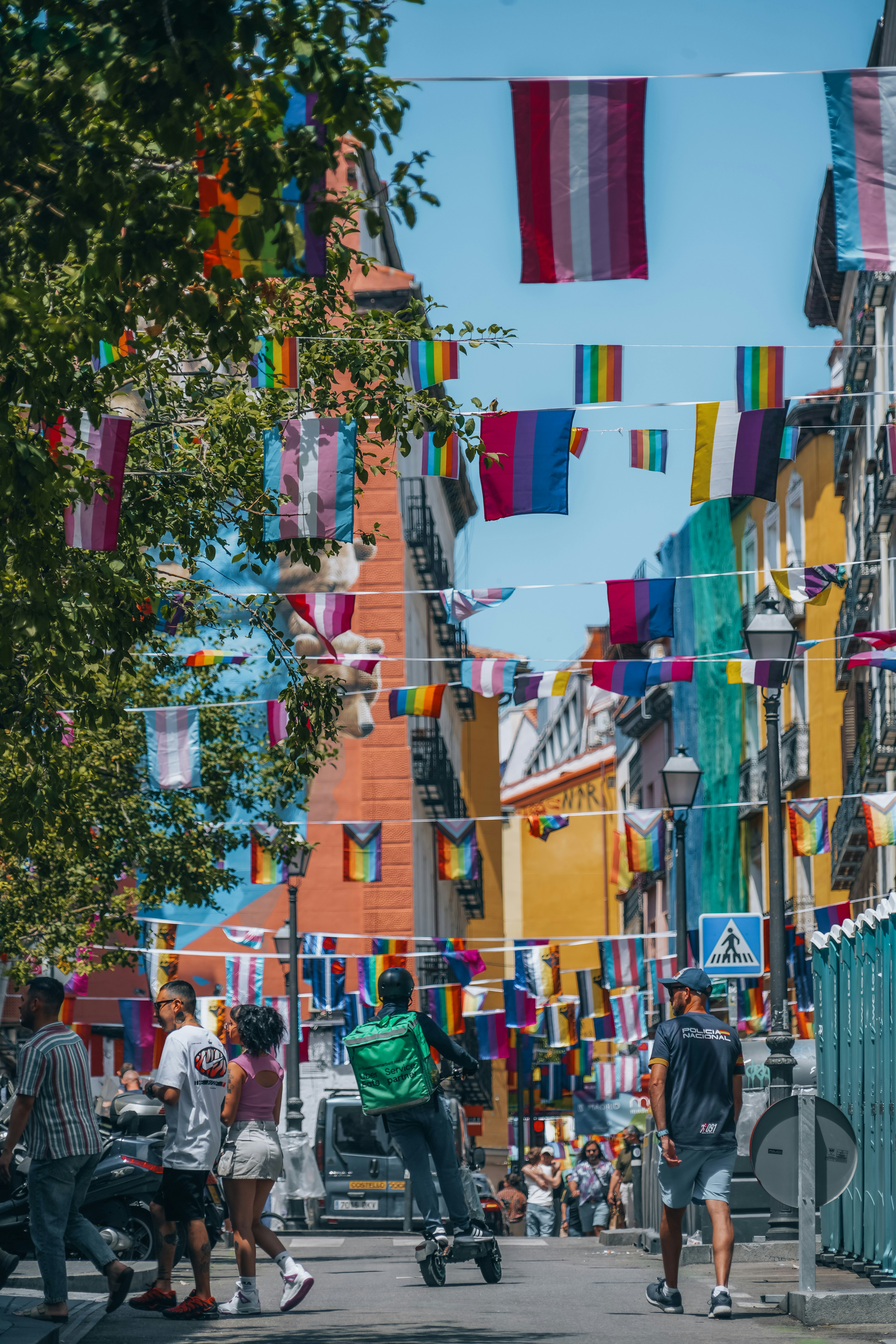 A group of people walking down a street next to tall buildings