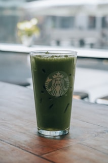 A green drink sitting on top of a wooden table