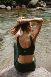 A woman sitting on a rock in front of a river
