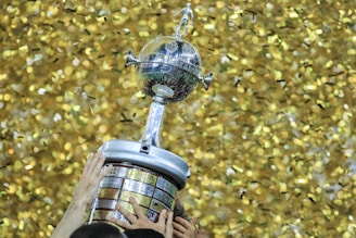 A person holding a trophy in front of a wall of confetti
