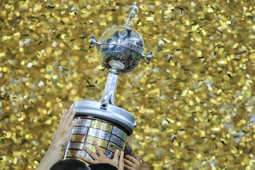 A person holding a trophy in front of a wall of confetti