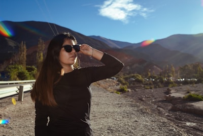 A woman in a black shirt and sunglasses standing on a dirt road