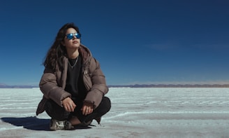 A woman sitting on the ground in the middle of nowhere