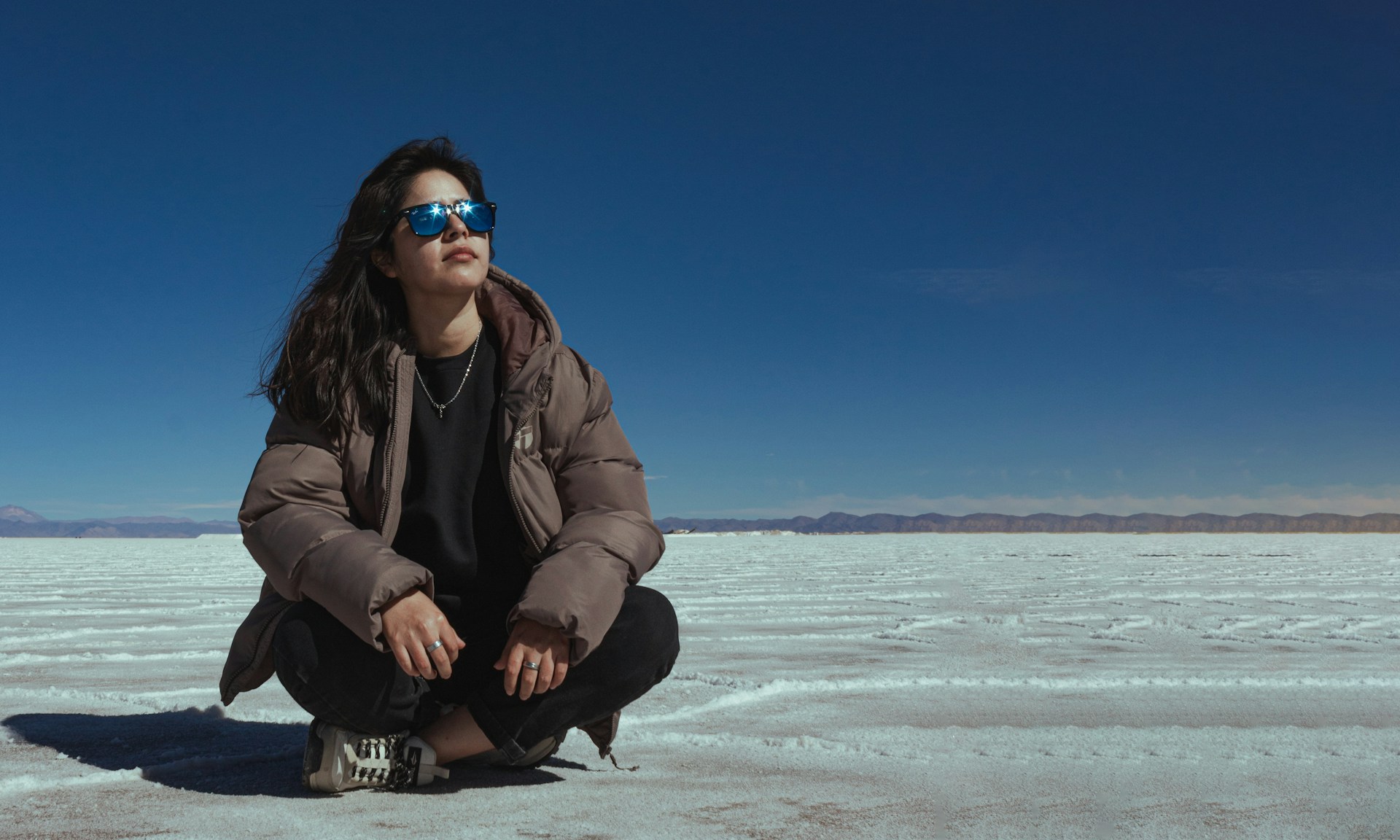 A woman sitting on the ground in the middle of nowhere
