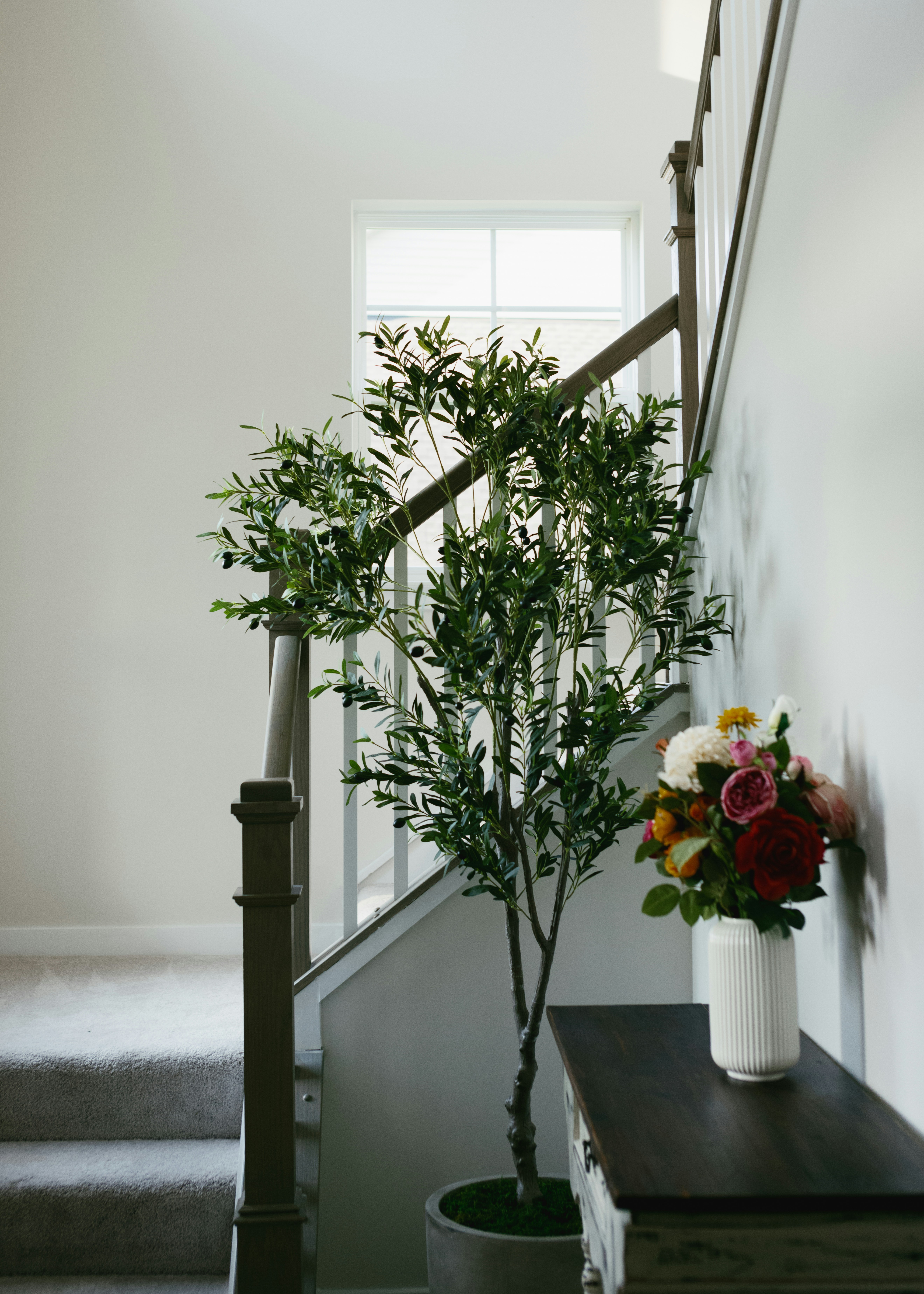 A vase of flowers sitting on a table next to a stair case