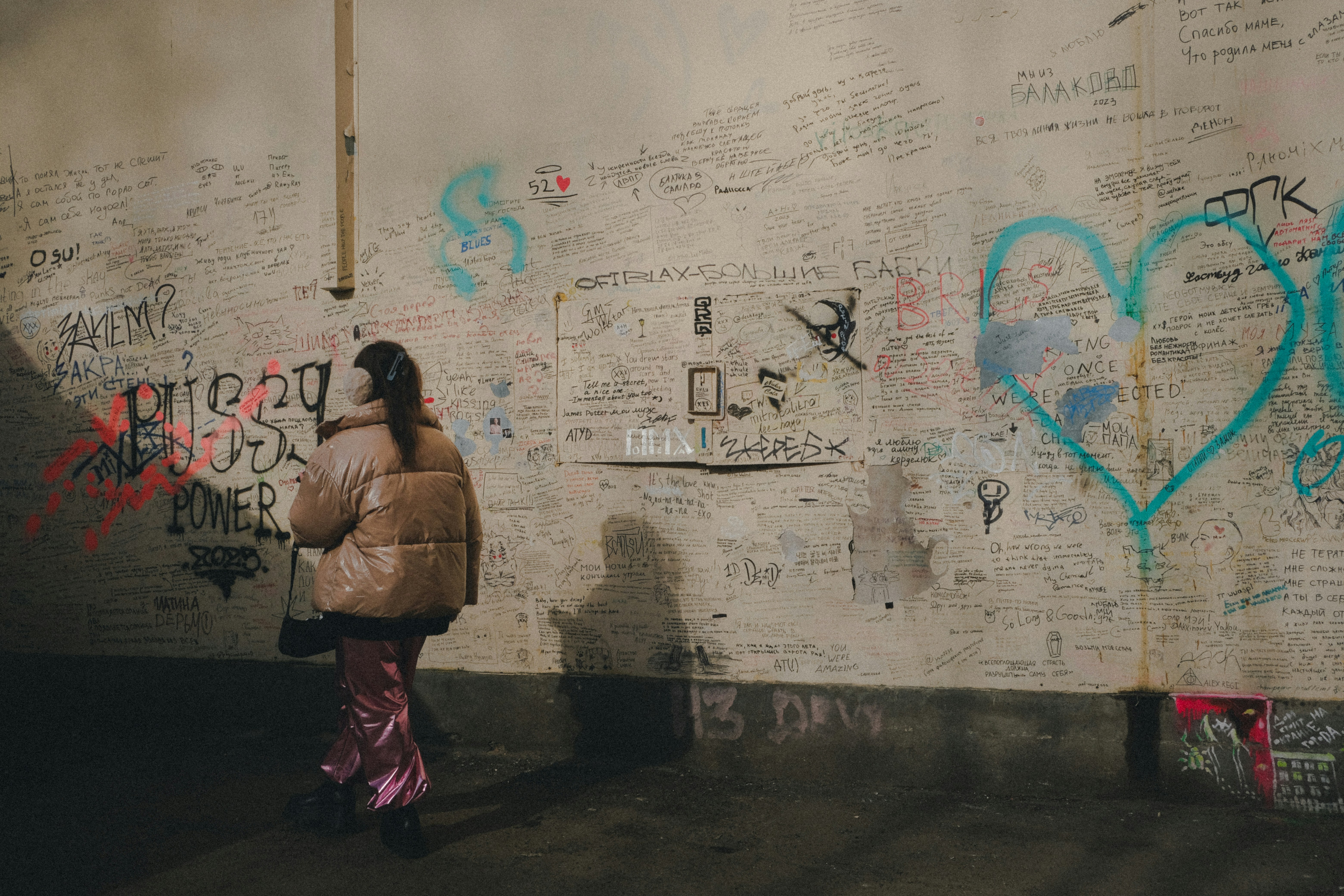 A woman standing in front of a wall covered in graffiti