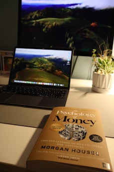 A laptop computer sitting on top of a desk next to a book