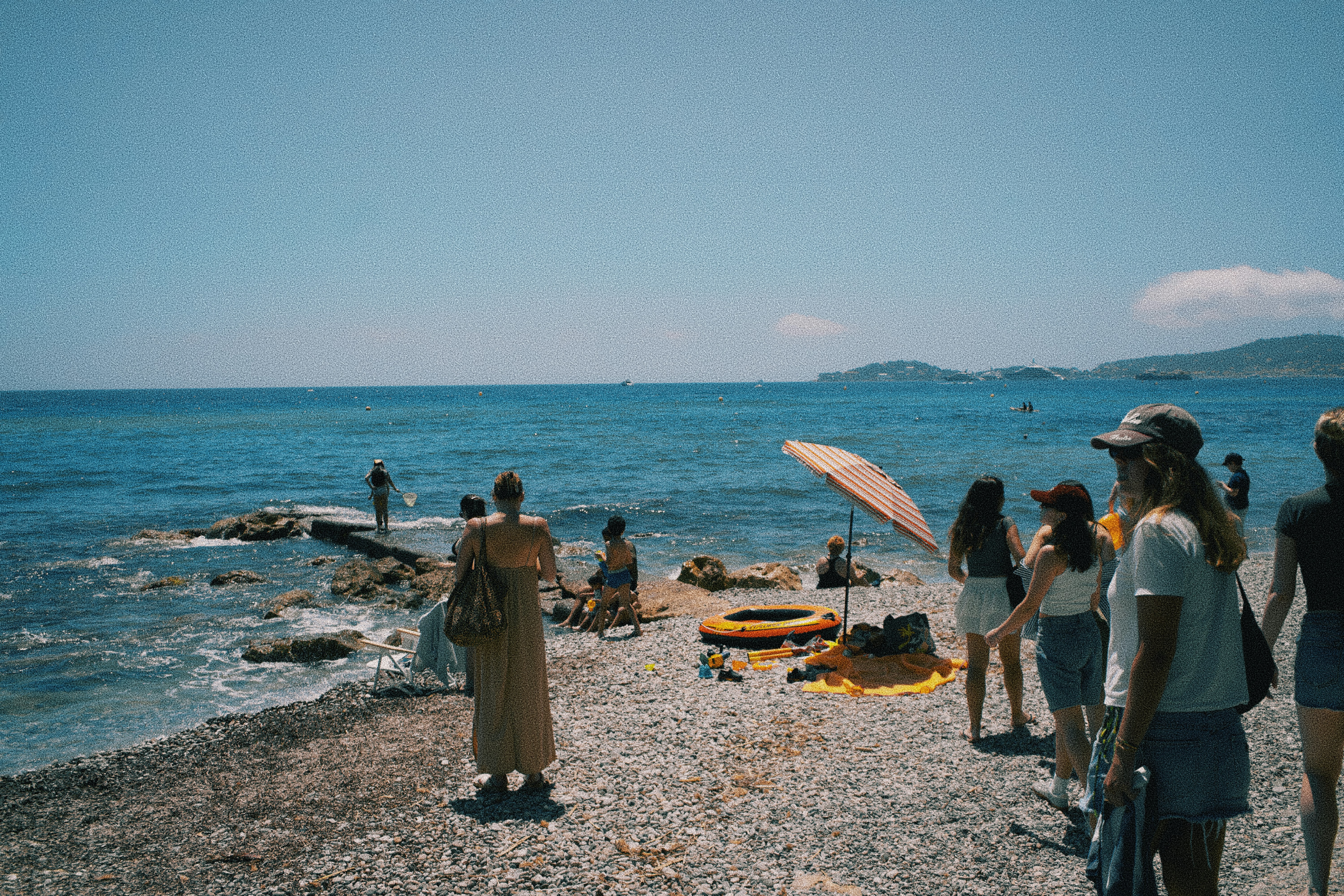 A group of people standing on top of a beach next to the ocean