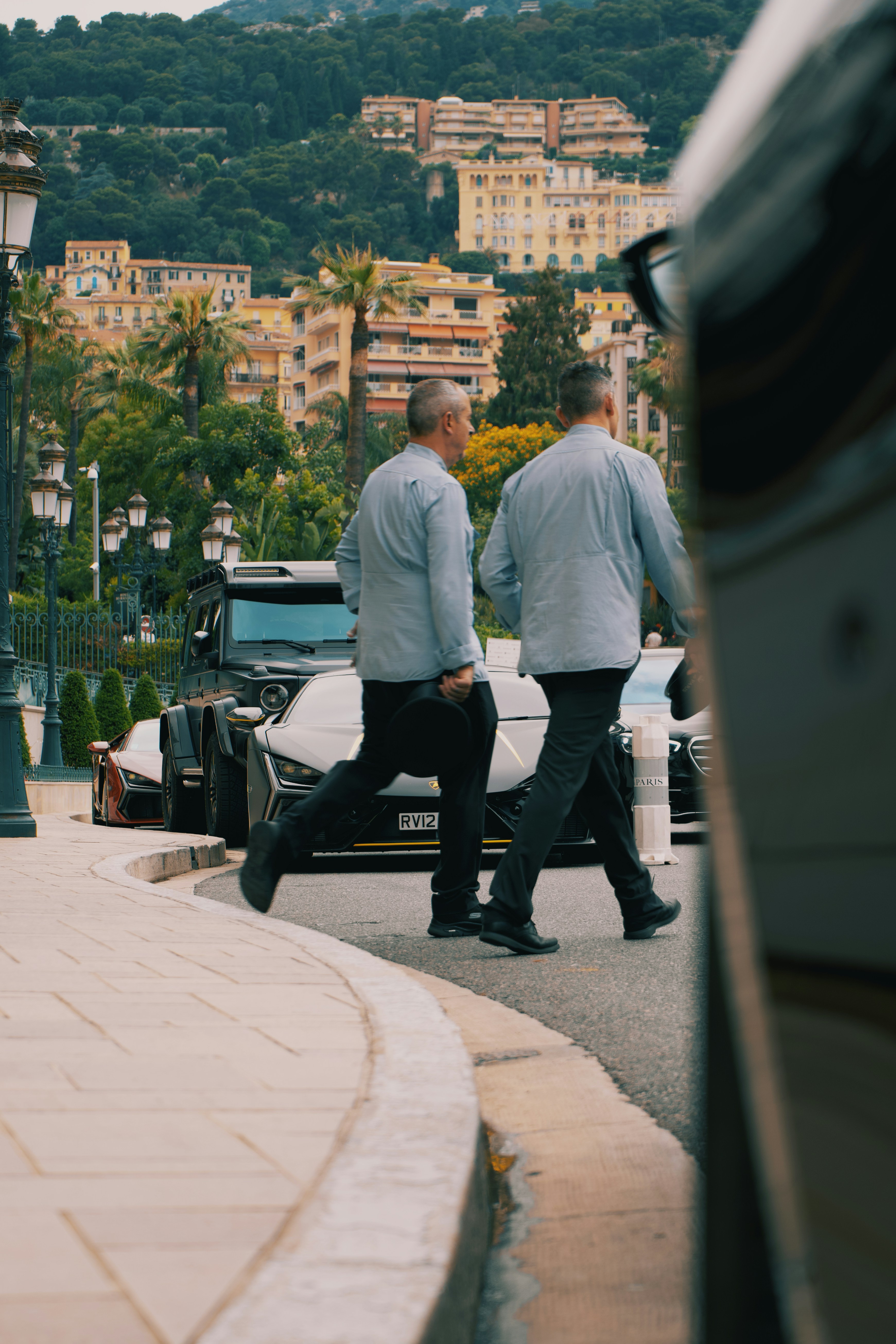 A couple of men walking down a street next to a car