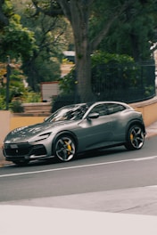 A grey ferrari purosangue driving down a street