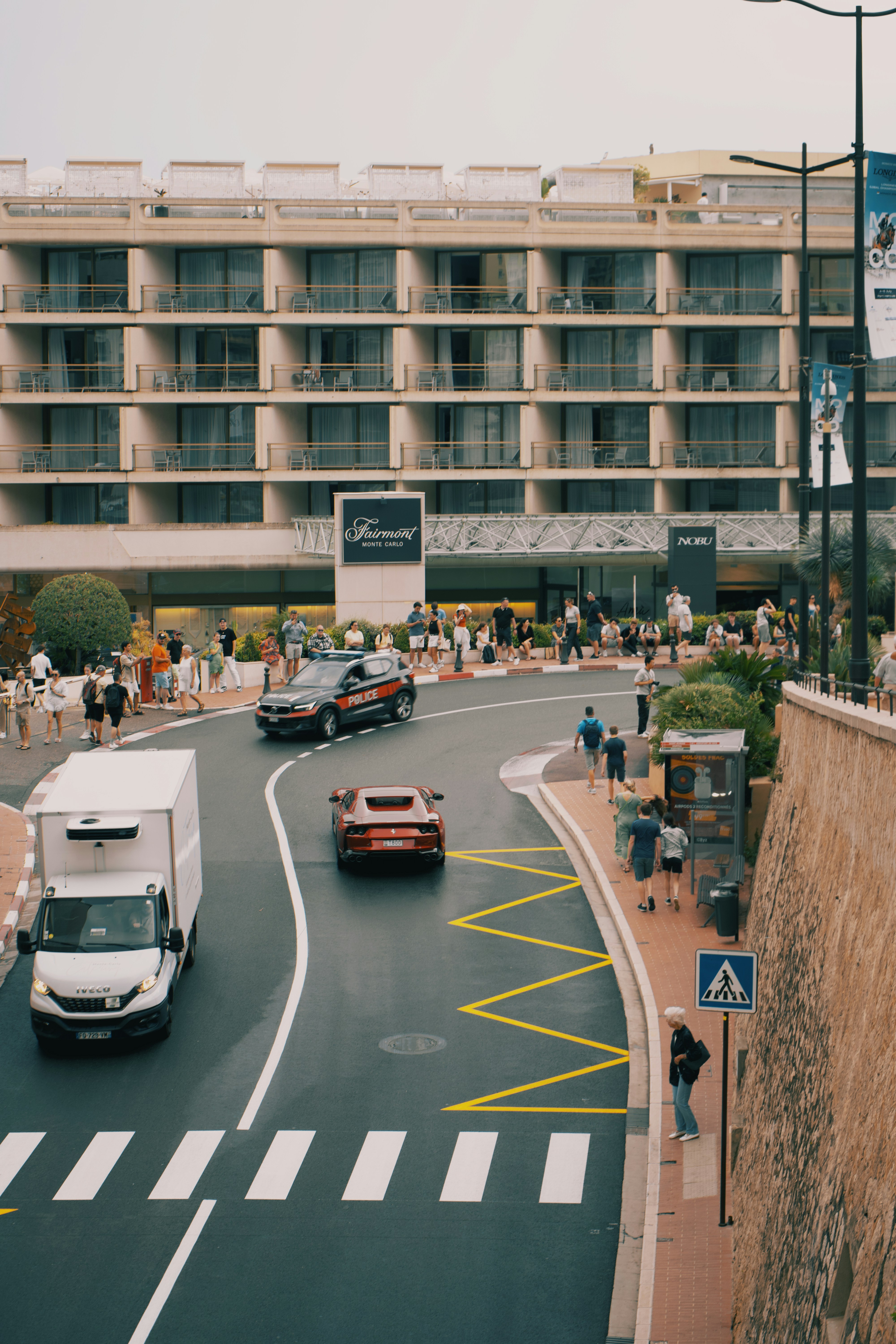 A busy street with cars and people walking on the sidewalk
