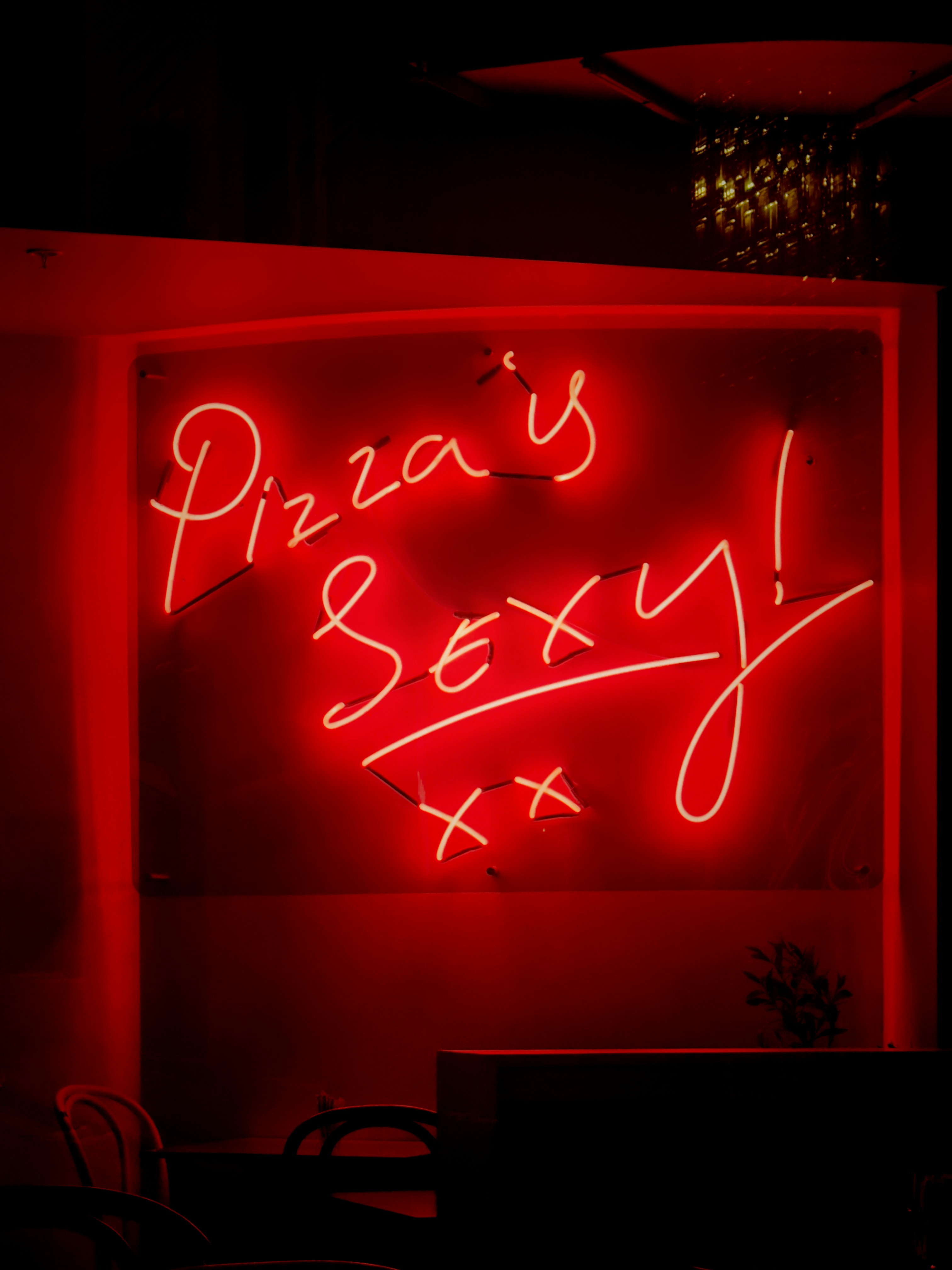 A red neon sign that says pizza's sexy