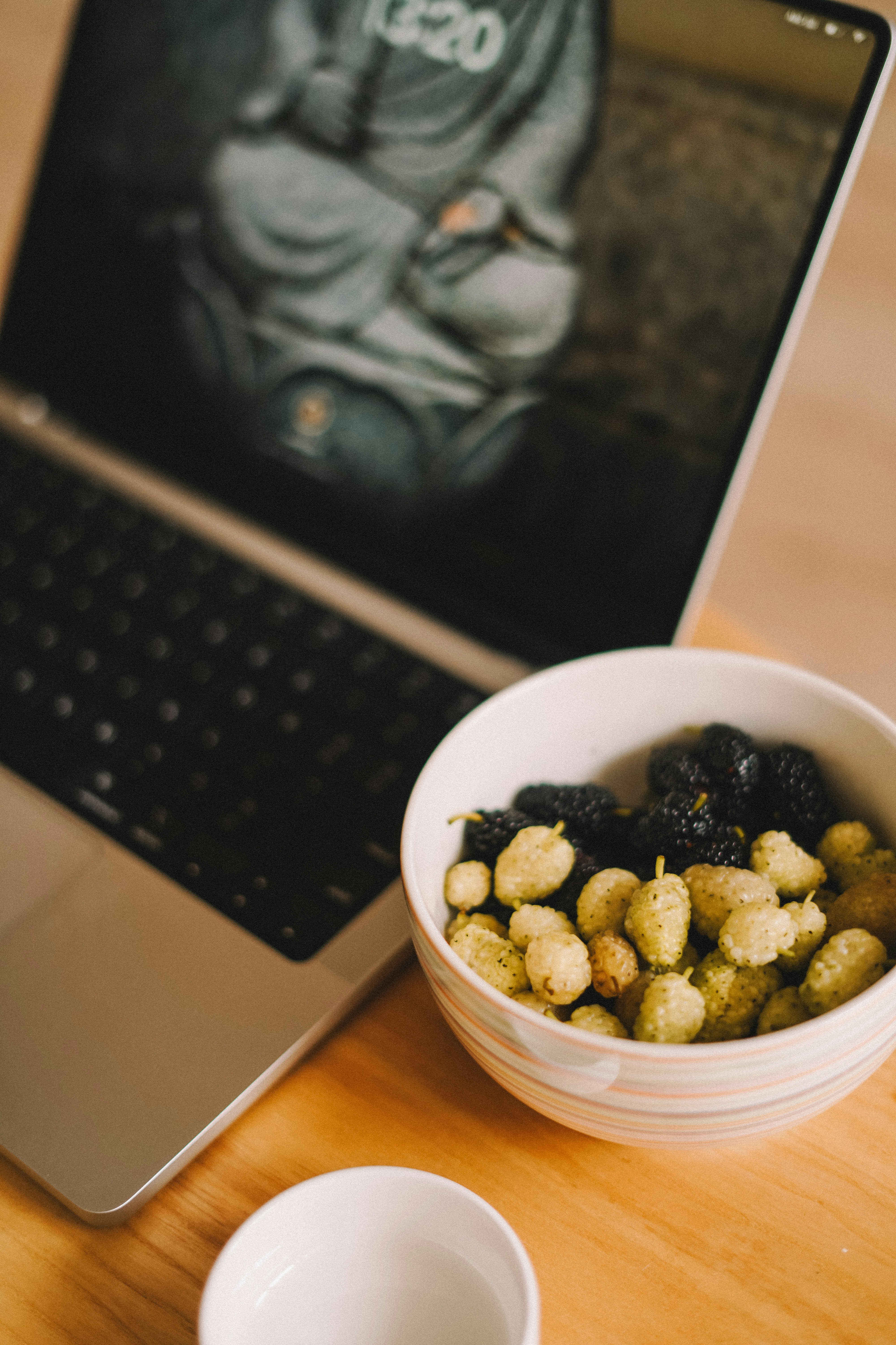 A bowl of food next to a laptop on a table