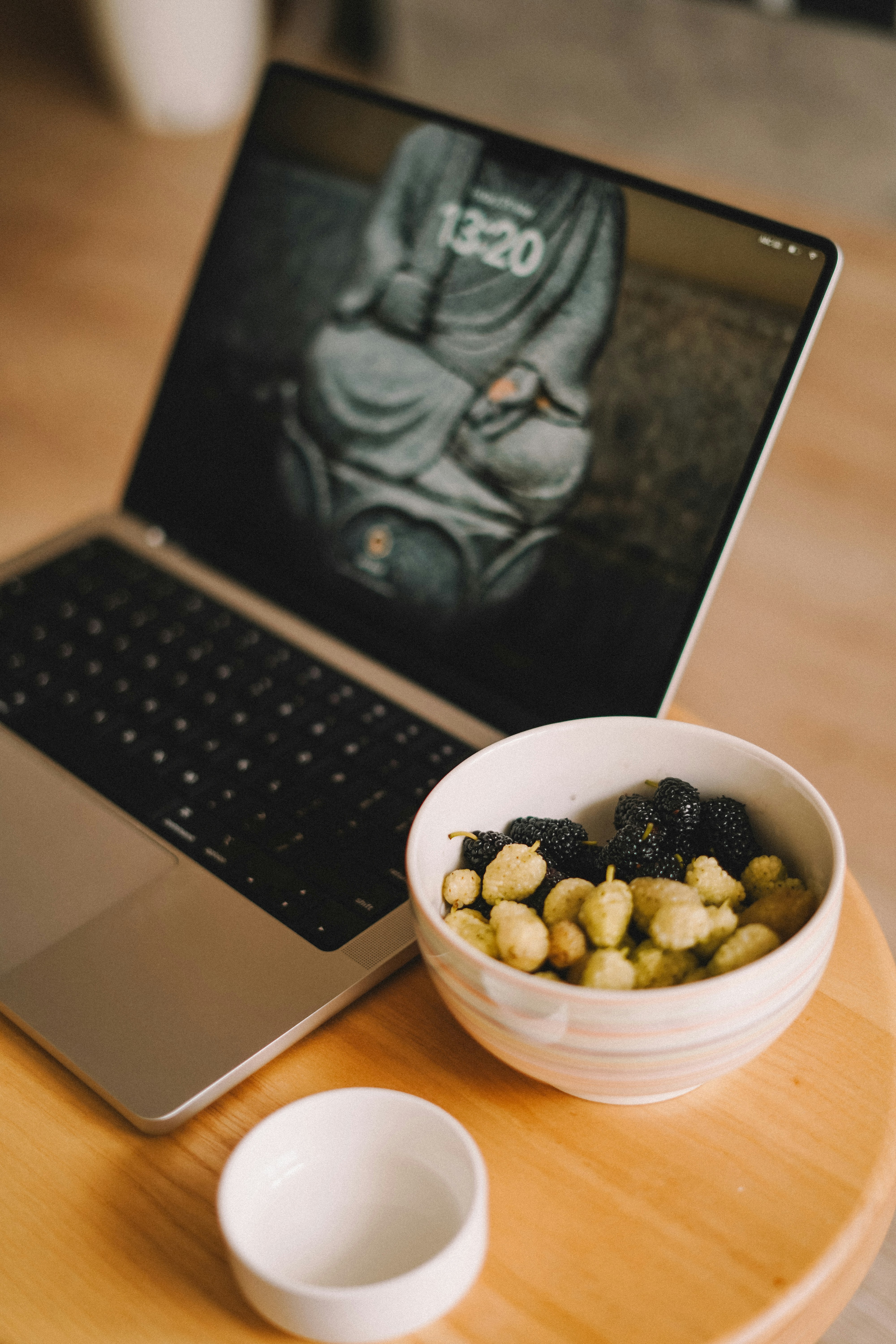 A bowl of cereal next to a laptop on a table