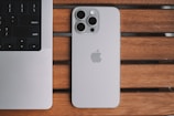 An iPhone and a laptop on a wooden table