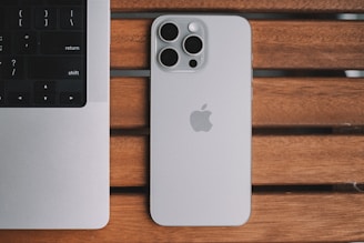 An iPhone and a laptop on a wooden table