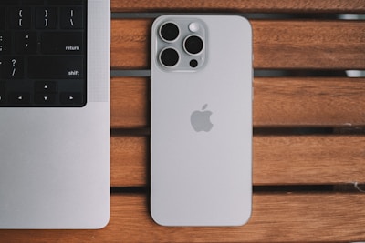 An iPhone and a laptop on a wooden table