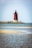 A red and white light house sitting on top of a small island