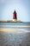 A red and white light house sitting on top of a small island
