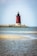 A red and white light house sitting on top of a small island