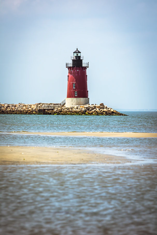 A red and white light house sitting on top of a small island