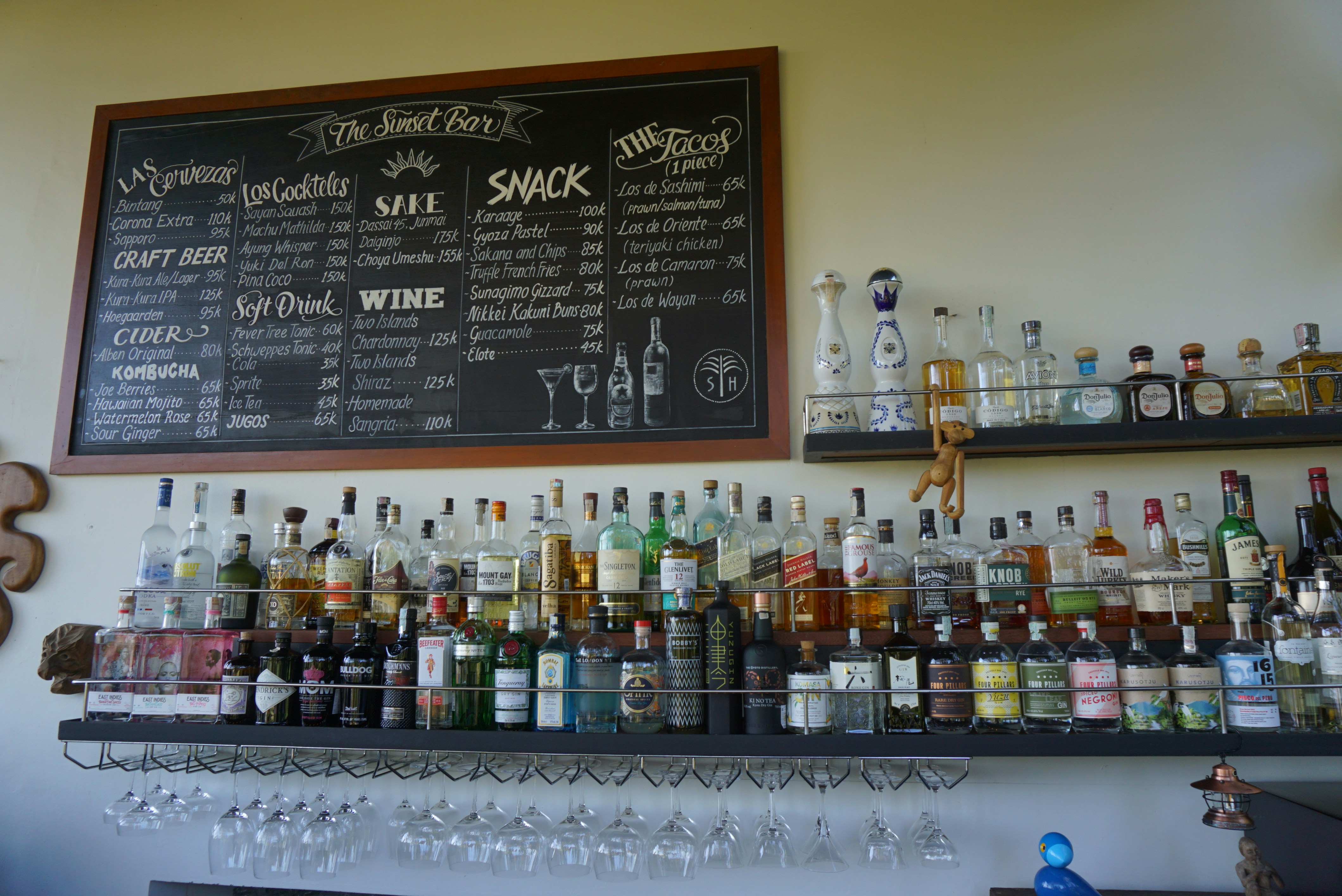 Liquor bottles on shelves below a chalkboard drinks menu