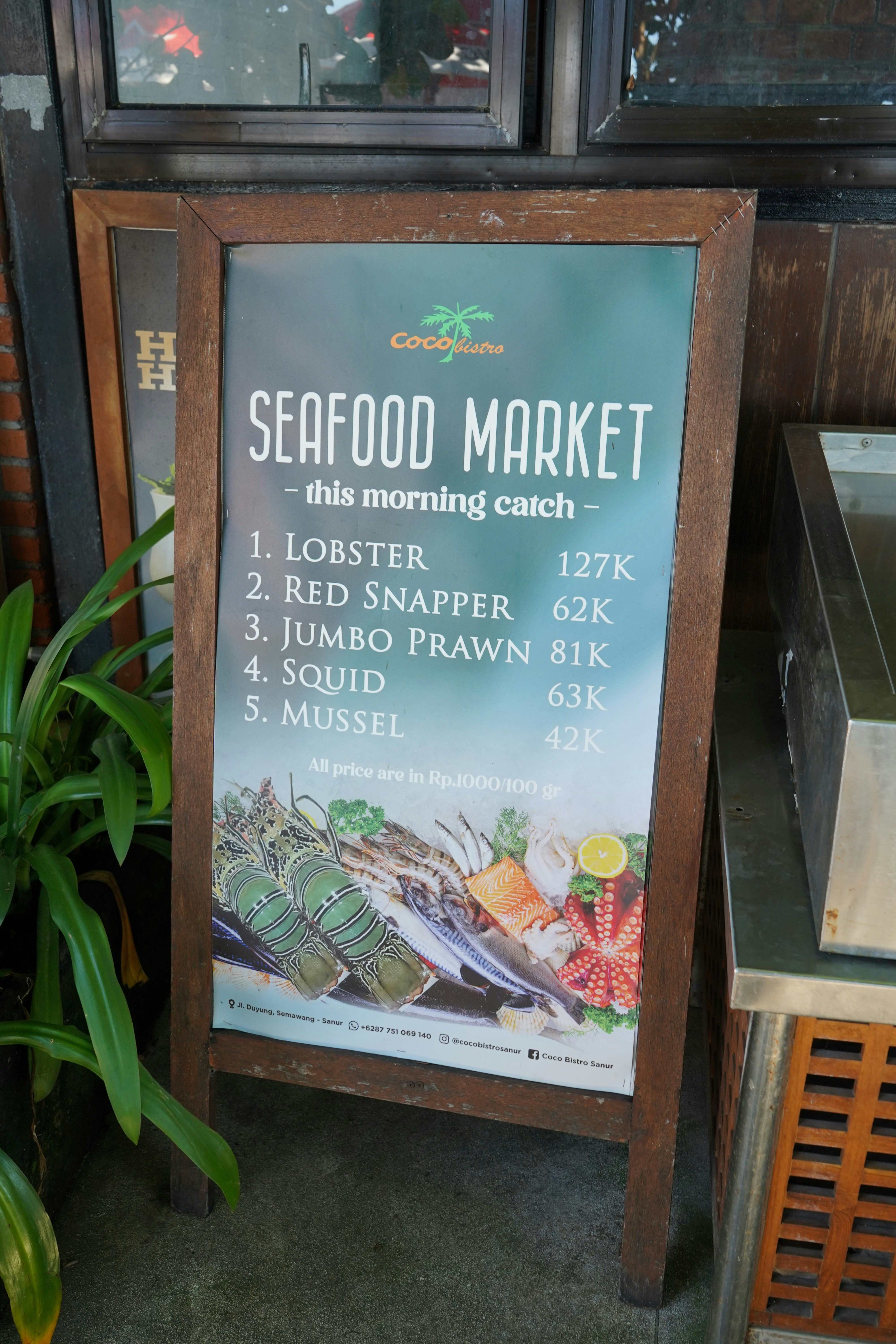 A sign advertising seafood market next to a potted plant