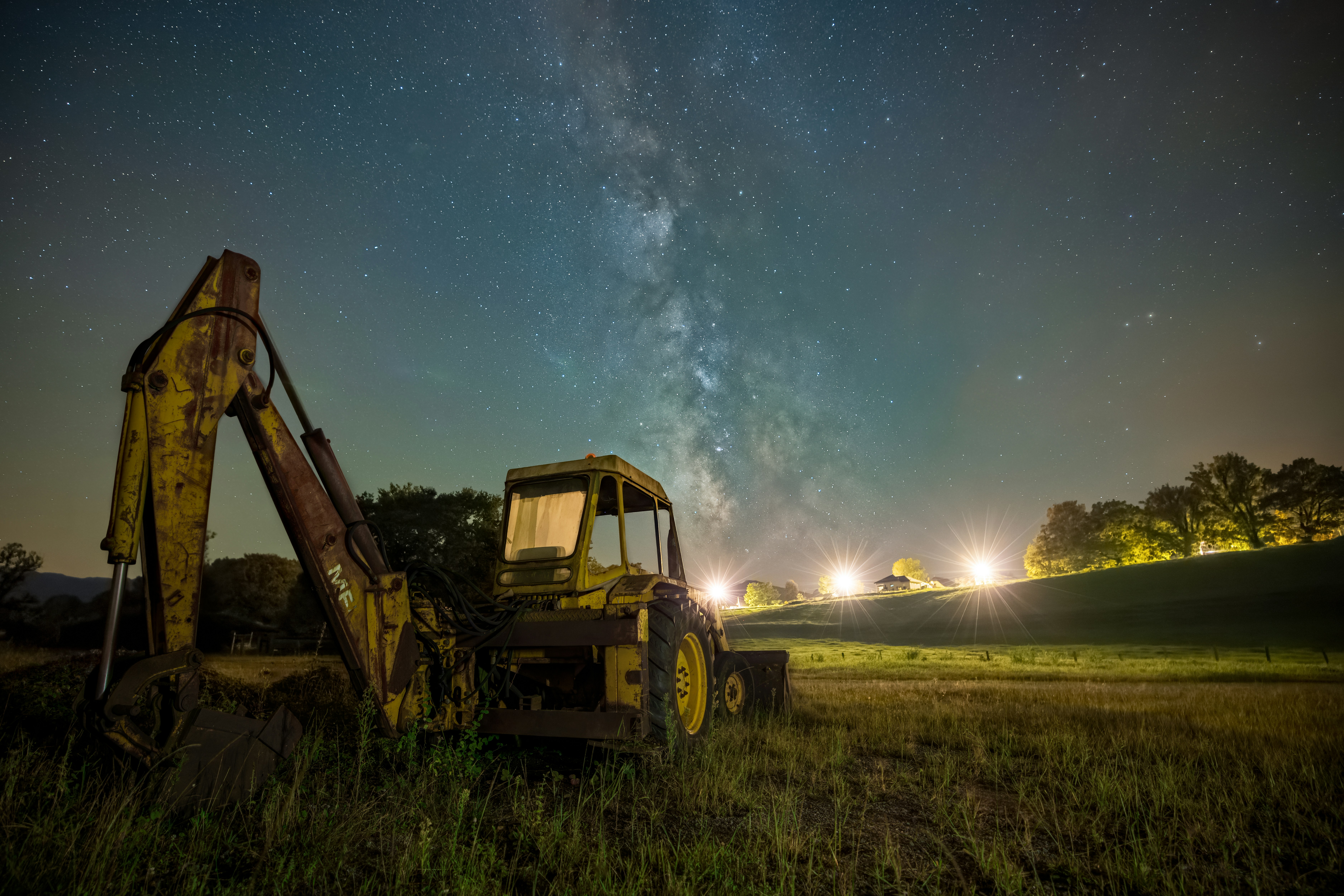 A tractor parked in a field with the milky in the background