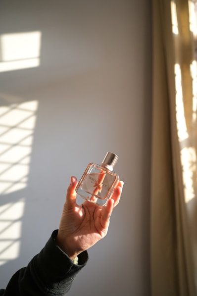A person holding a bottle of perfume in their hand