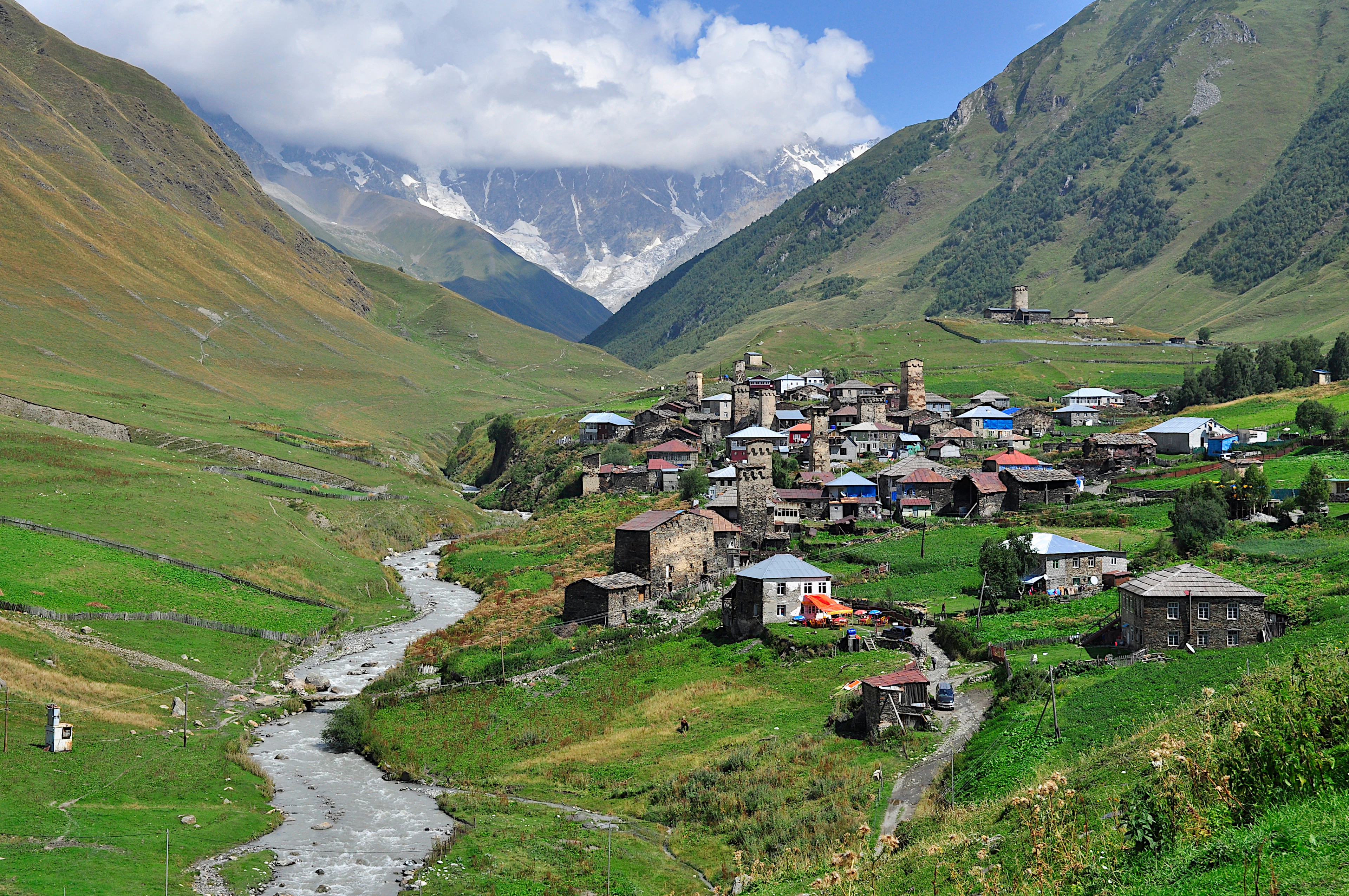 Ushguli village and its stone Svan towers in a green valley, with the Caucasus rising into cloud behind, Svaneti, Georgia