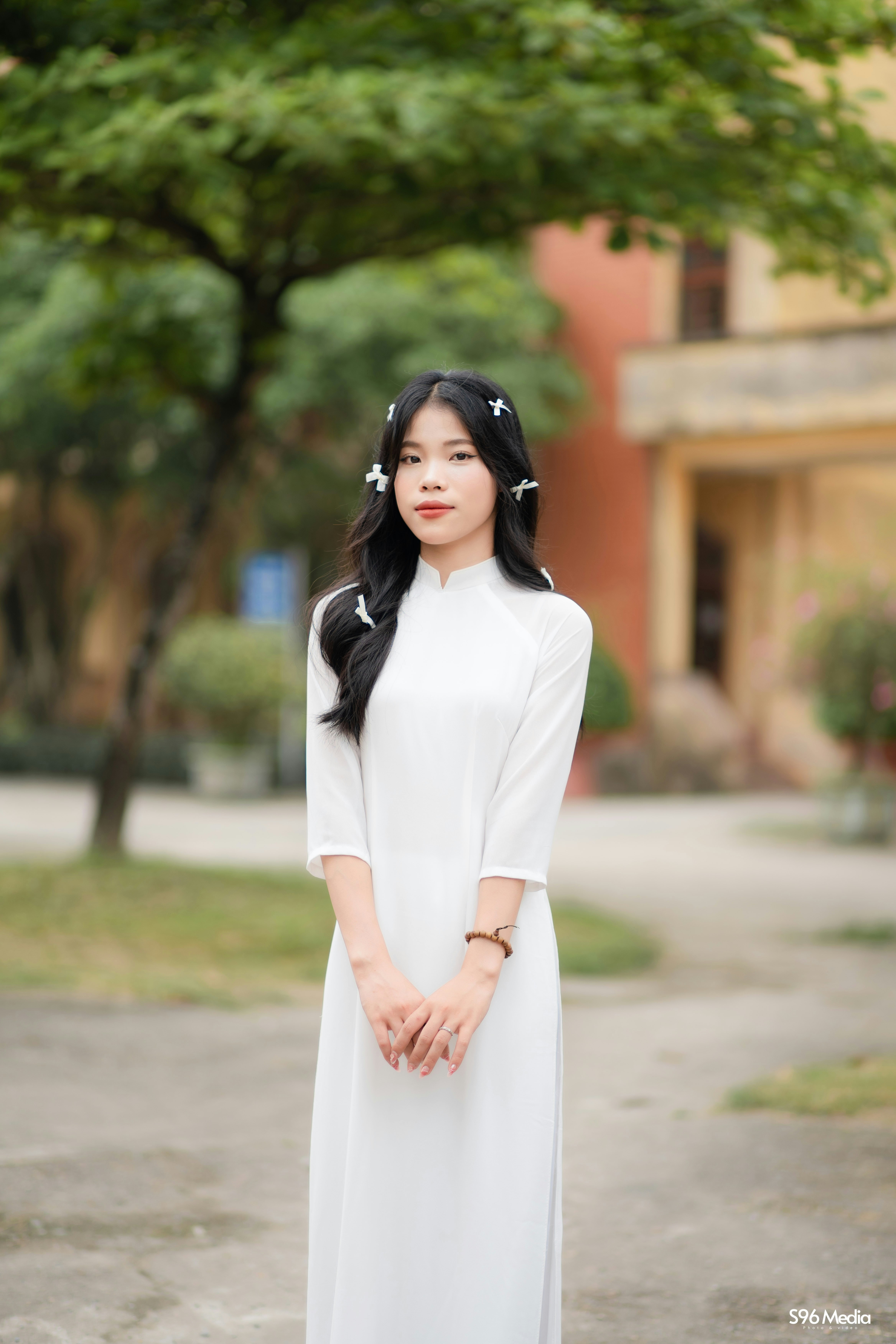 A woman in a white dress standing in front of a tree