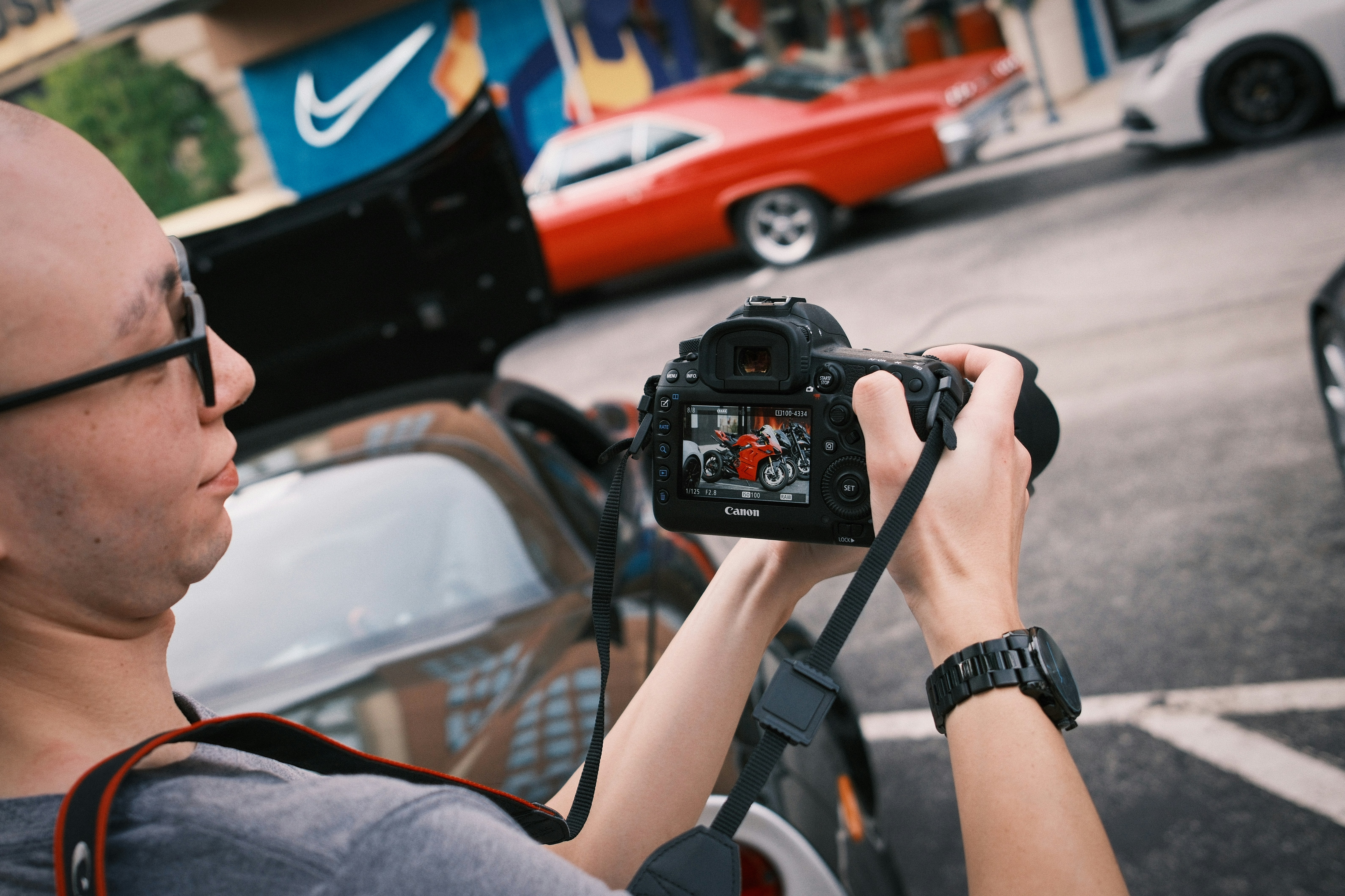 빨간 차의 사진을 찍는 남자