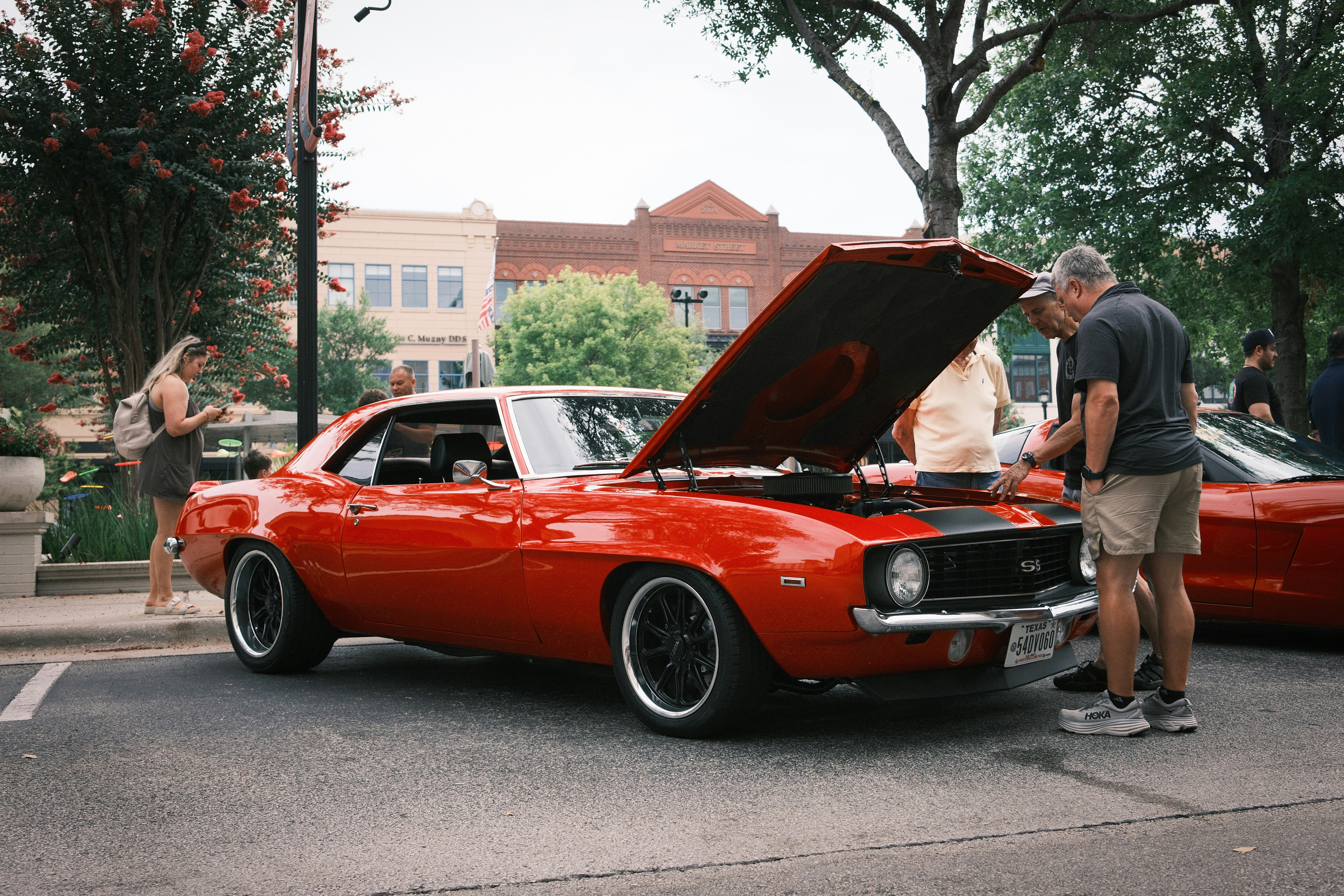 빨간 차 옆에 보닛이 열린 채 서 있는 남자