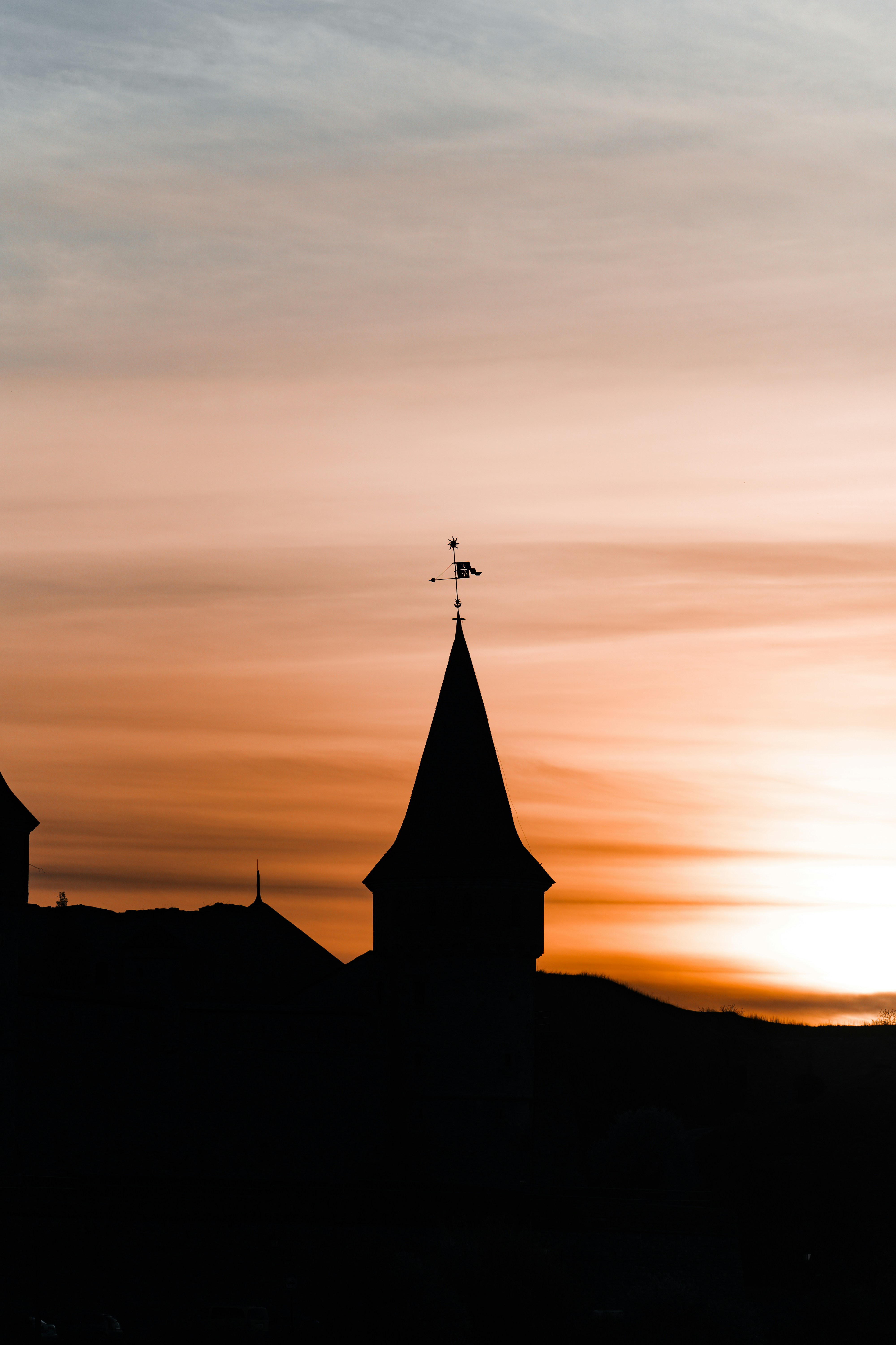 The sun is setting behind a church steeple