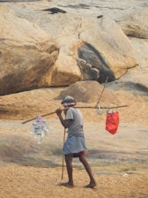 A man holding a stick on top of a sandy beach
