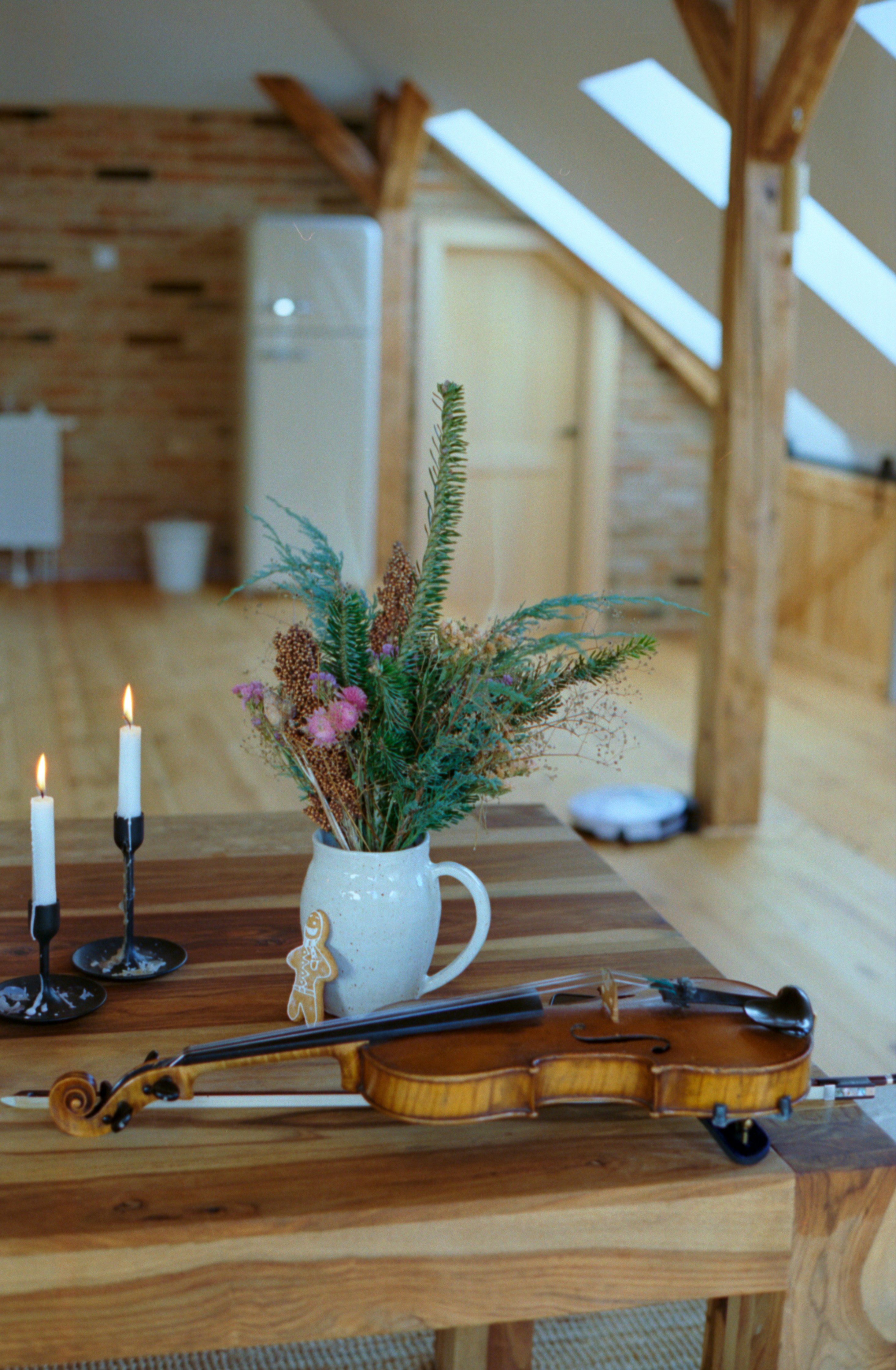 A wooden table topped with a violin and a vase filled with flowers