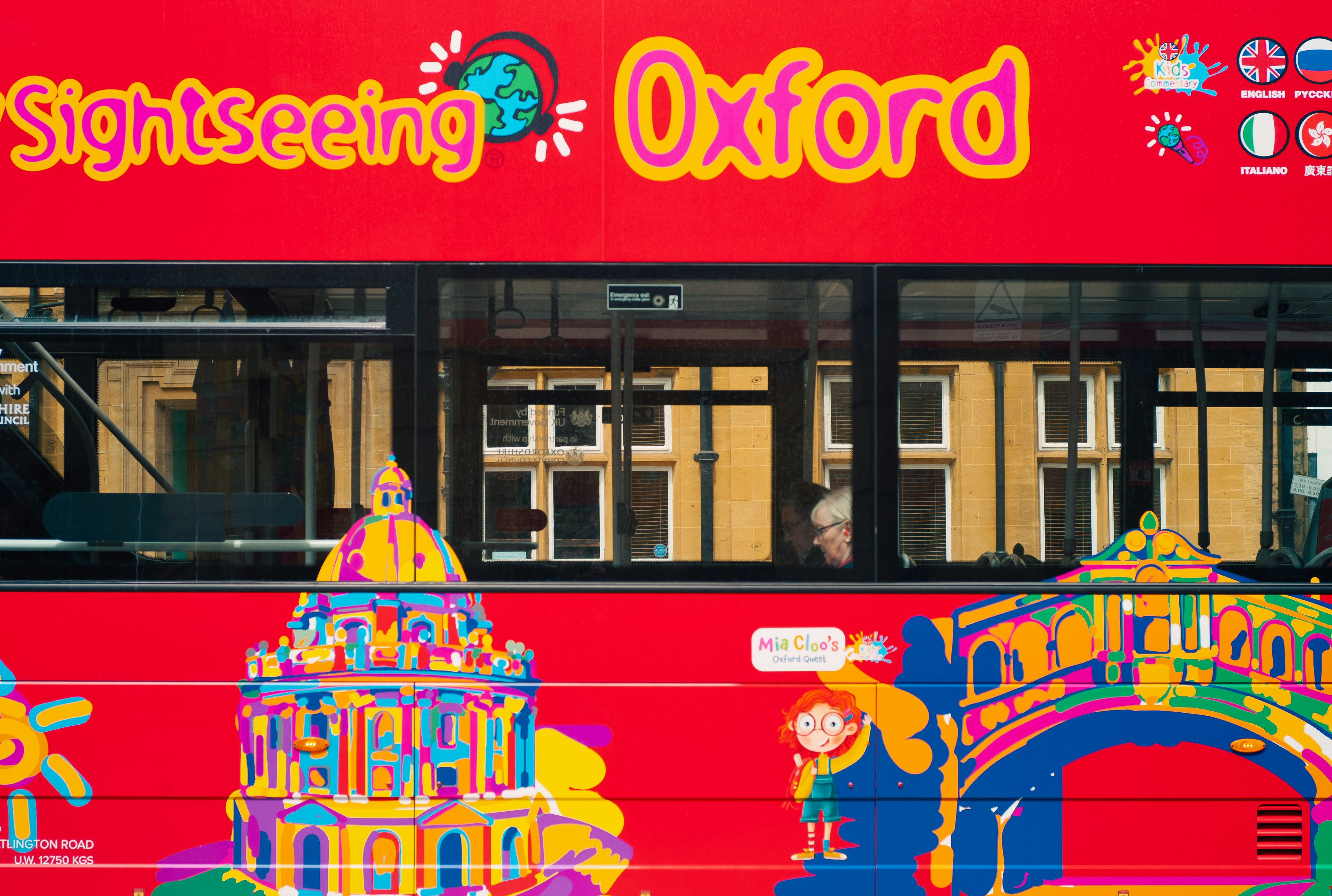 A red double decker bus parked in front of a building