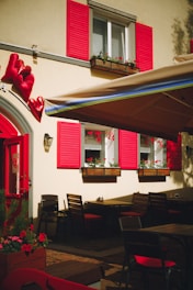 A restaurant with red shutters and tables and chairs