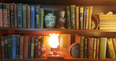 A bookshelf filled with lots of books and a lit candle